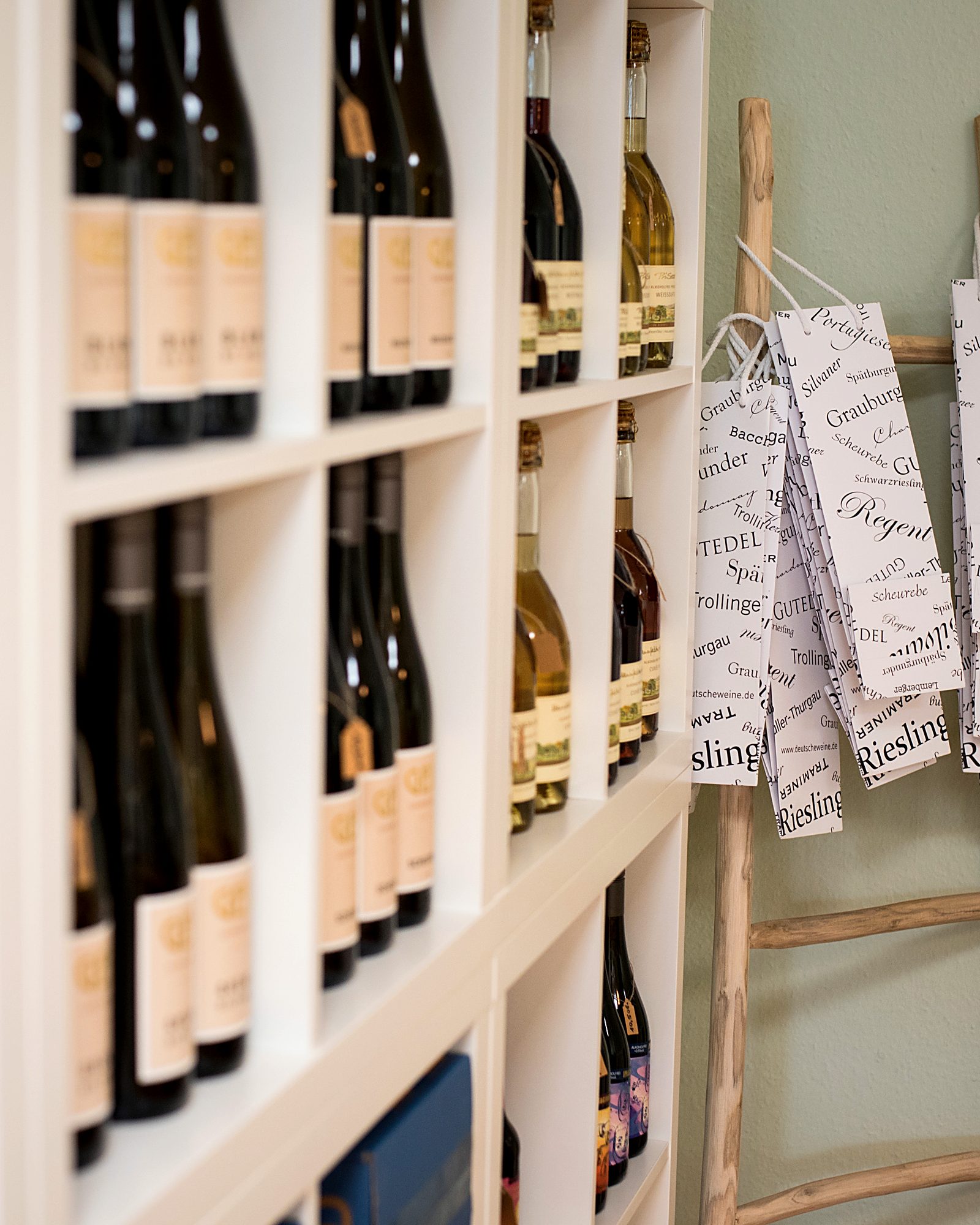 Weinregal im Billerbecker Weinbüdchen, daneben eine Holzleiter mit Flaschentaschen
