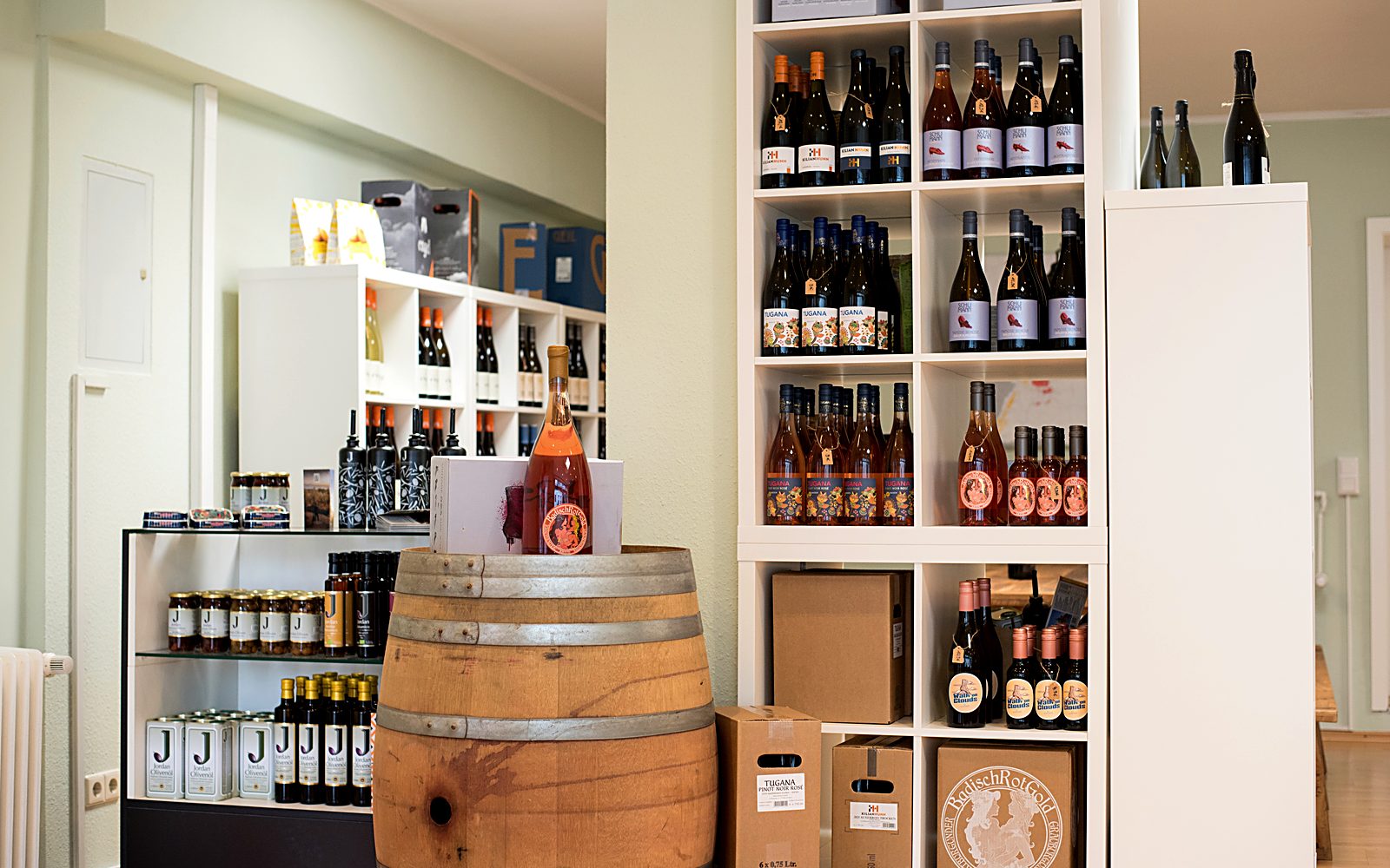 Blick in das Weinbüdchen: Weinregal, Holzfass und Delikatessen-Regal