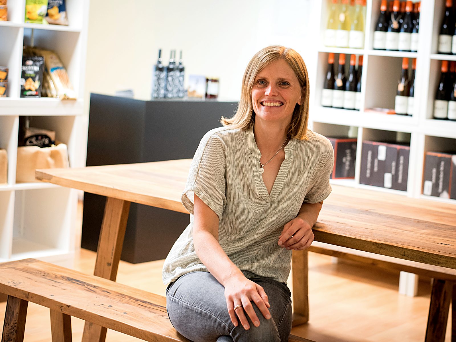 Hanna Köhler am Tisch im Weinbüdchen, im Hintergrund die Weinregale